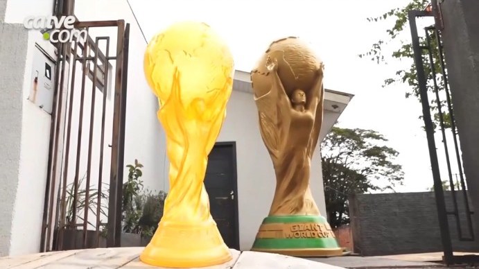 Two World Cup replicas, a small yellow one in the foreground and the giant golden one behind