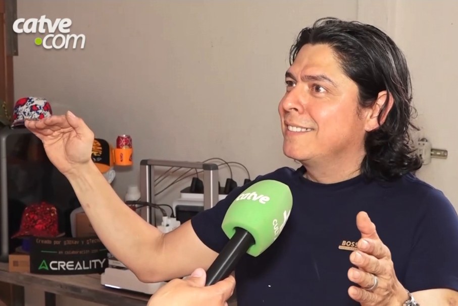 Long-haired man interviewed in a 3D printing workshop