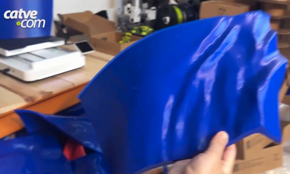 Hand holding a large blue 3D-printed part