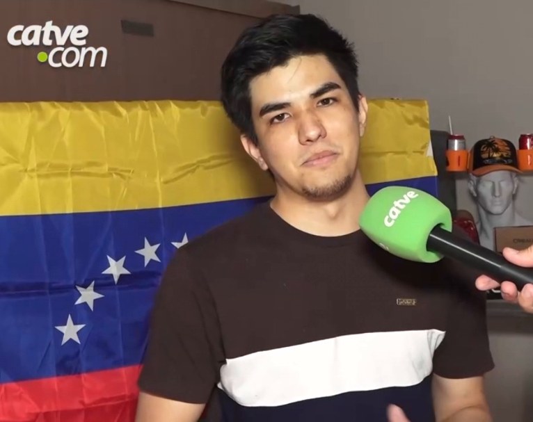 Young man interviewed in front of a Venezuelan flag