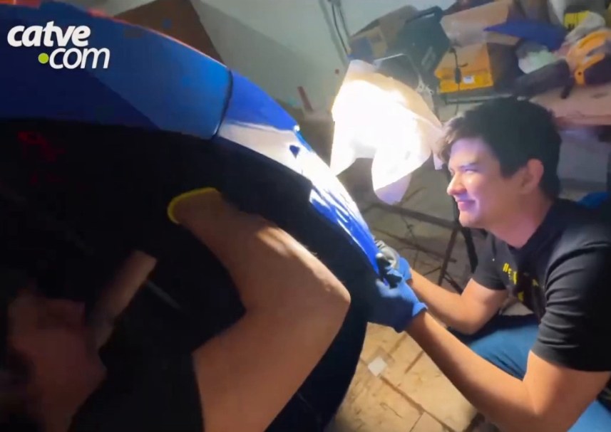 Two people joining blue parts, one of them inside the structure