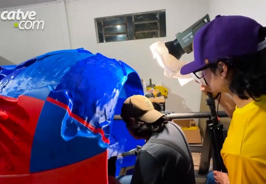 Two people working on the globe made of blue and red parts