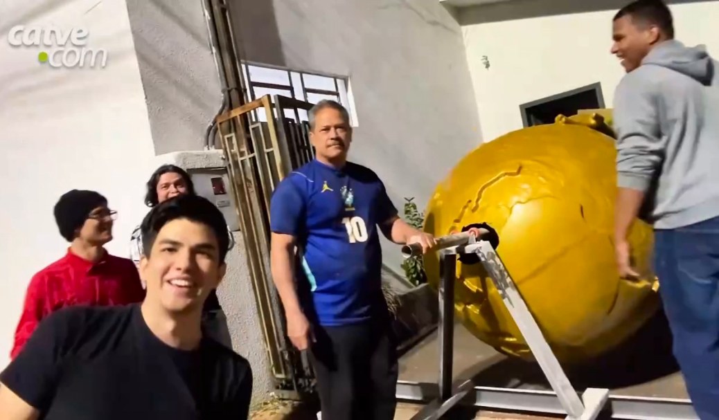 Five smiling people around the golden globe of the trophy