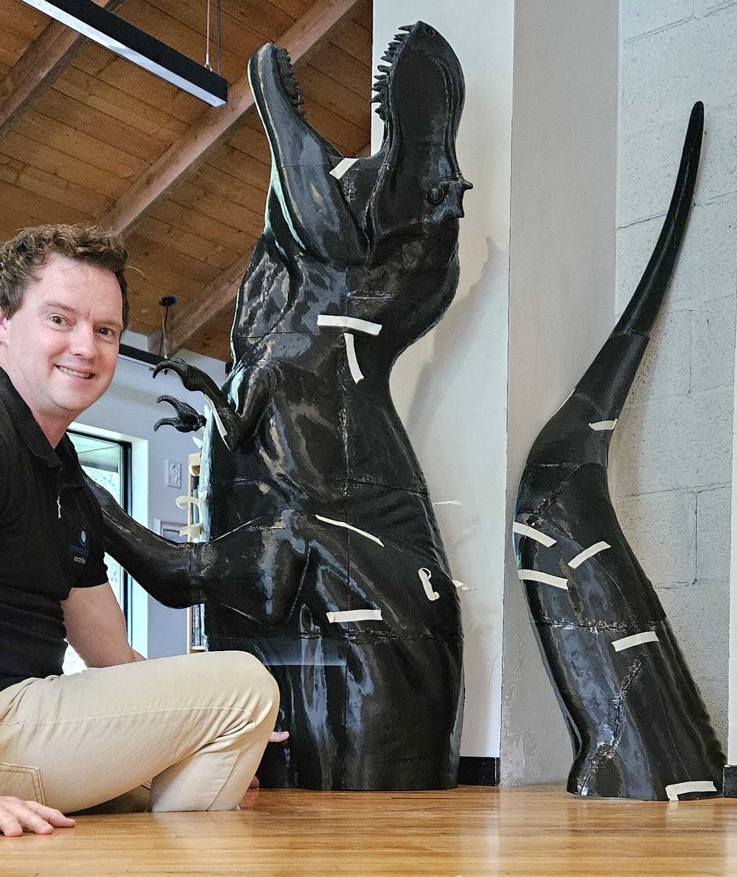 Tim Boyle sitting next to the T. rex body and tail, parts marked with tape