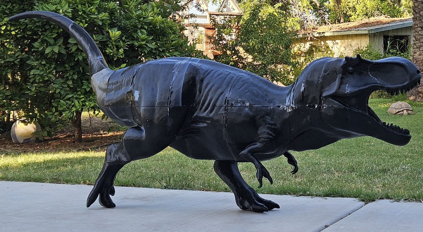 Black 3D-printed T. rex, assembled, side view on a patio